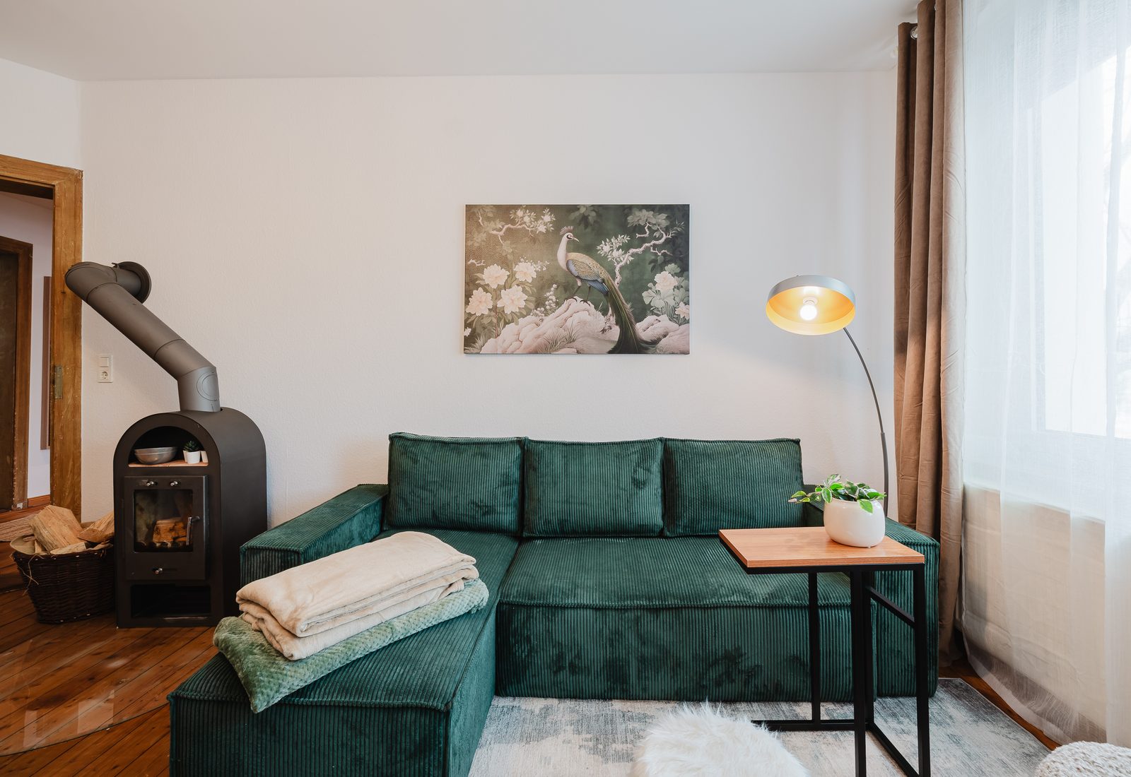 Wohnzimmer des Altbautraums mit grünem Samtsofa und Kaminofen