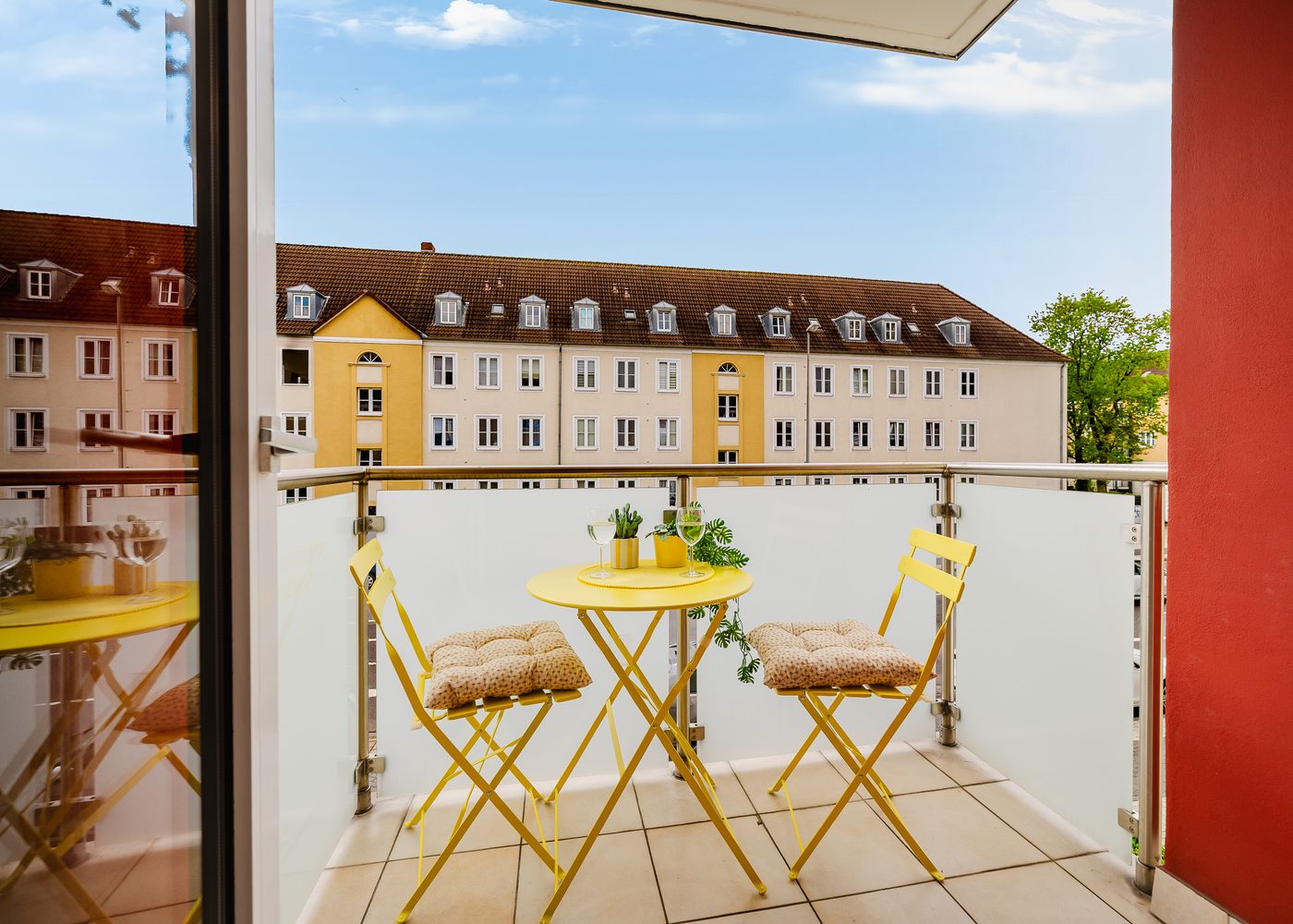 Balkon des Beetle Apartments in Wolfsburg mit gelbem Bistrotisch und zwei Stühlen